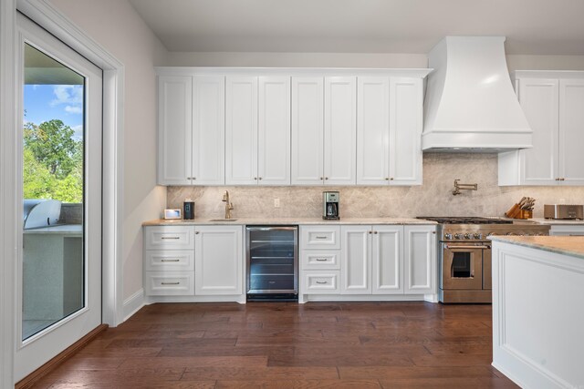 kitchen with wine cooler, double oven range, custom exhaust hood, decorative backsplash, and white cabinets
