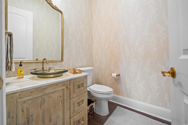 bathroom with toilet, baseboards, and vanity