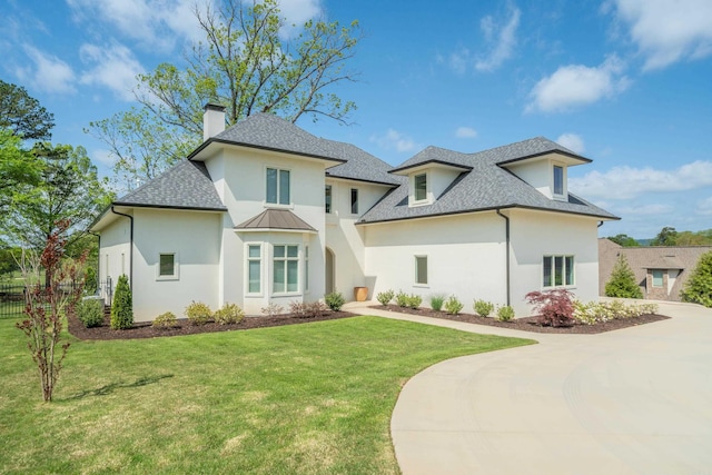 view of front of home featuring stucco siding, a chimney, fence, a shingled roof, and a front lawn