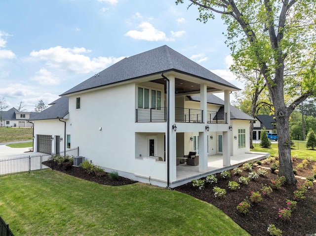 rear view of house with a yard, fence, stucco siding, and a balcony