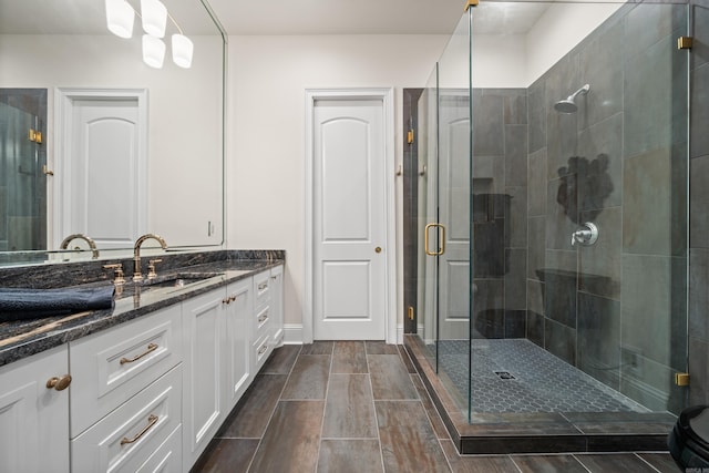full bathroom with a stall shower, vanity, and wood finish floors