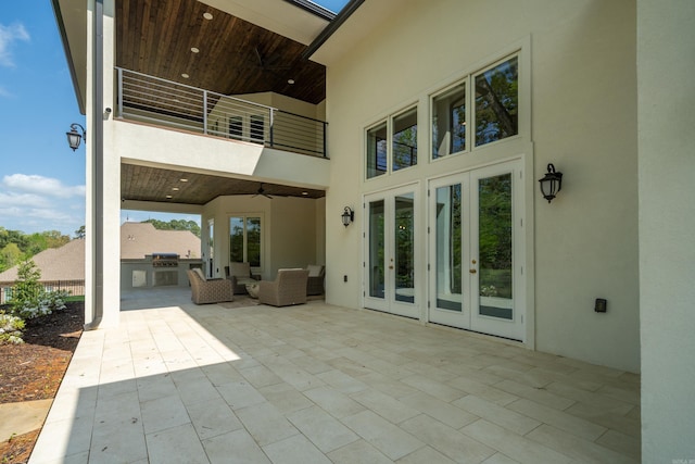 rear view of property featuring a balcony, stucco siding, french doors, and exterior kitchen