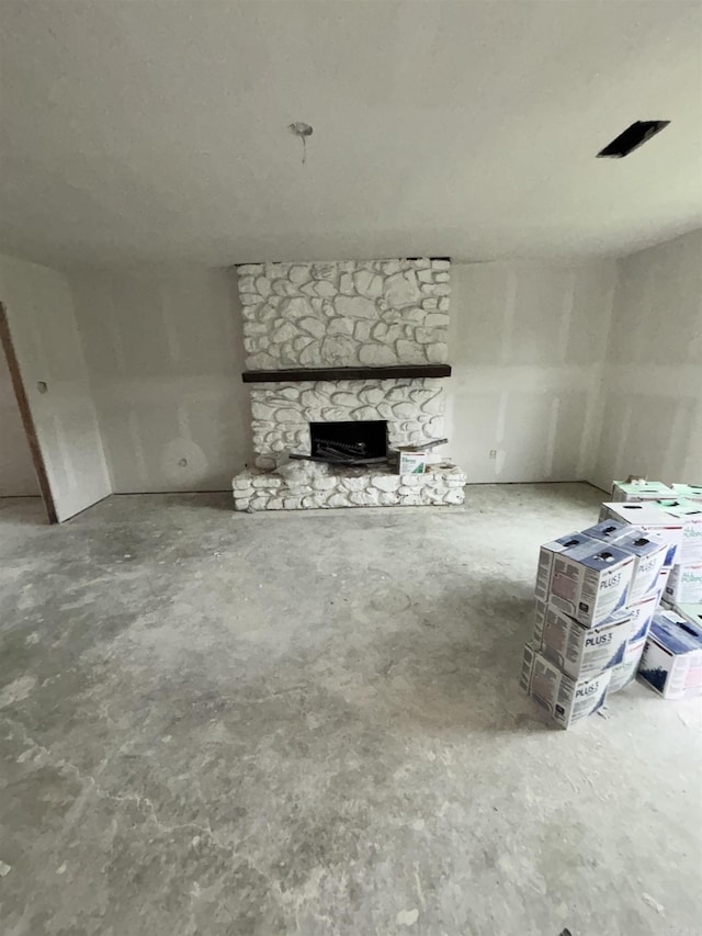 unfurnished living room with concrete floors and a stone fireplace