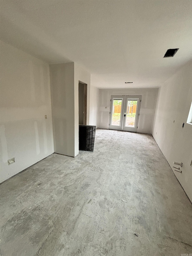 unfurnished room with unfinished concrete flooring and french doors