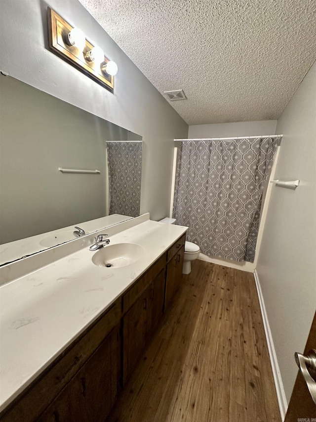 12921 Barth Rd, Alexander, AR 72002 - full bath featuring a textured ceiling, wood finished floors, toilet, vanity, and baseboards