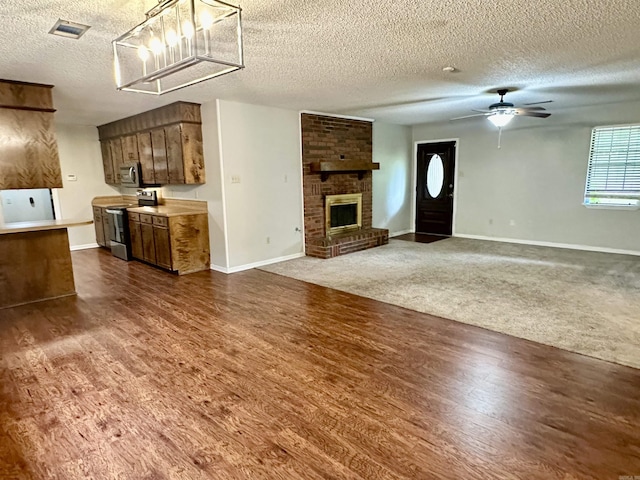 12921 Barth Rd, Alexander, AR 72002 - unfurnished living room featuring a textured ceiling, baseboards, dark wood-style floors, a ceiling fan, and a brick fireplace