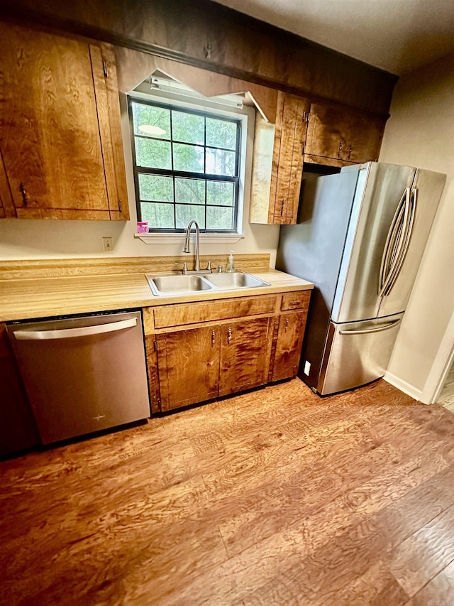 12921 Barth Rd, Alexander, AR 72002 - kitchen featuring appliances with stainless steel finishes, a sink, light countertops, light wood-style floors, and brown cabinets