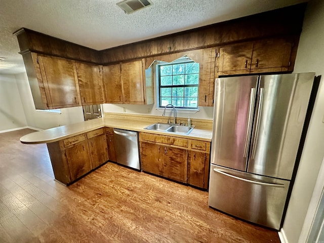 12921 Barth Rd, Alexander, AR 72002 - kitchen featuring stainless steel appliances, a sink, a textured ceiling, light countertops, and light wood-type flooring