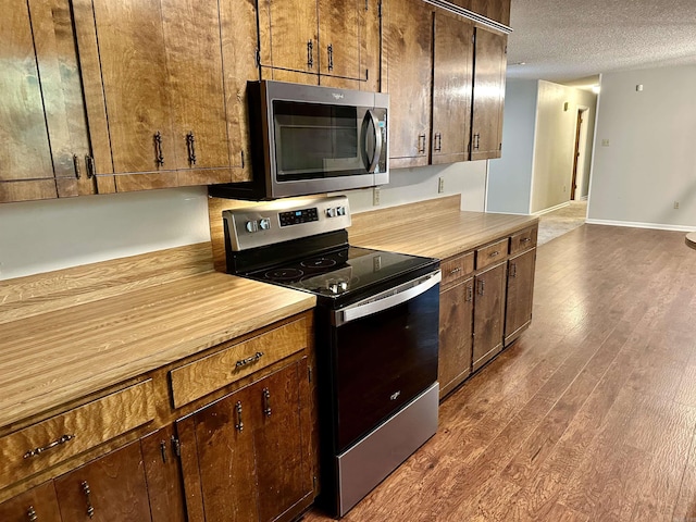 12921 Barth Rd, Alexander, AR 72002 - kitchen featuring appliances with stainless steel finishes, dark wood finished floors, a textured ceiling, and baseboards