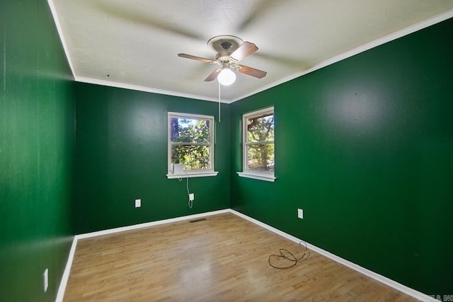 empty room featuring ceiling fan, baseboards, visible vents, and wood finished floors