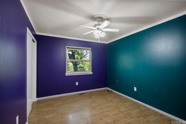 unfurnished room featuring a ceiling fan, baseboards, visible vents, crown molding, and wood finished floors