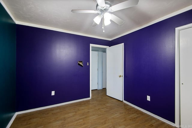 spare room featuring a ceiling fan, wood finished floors, baseboards, and ornamental molding