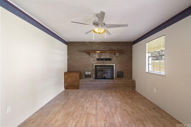 unfurnished living room featuring a ceiling fan, ornamental molding, visible vents, wood finished floors, and a fireplace