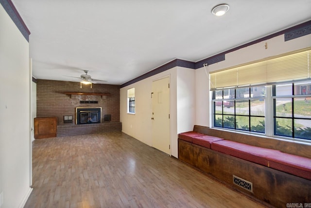 unfurnished living room with a wealth of natural light, a ceiling fan, visible vents, and wood finished floors