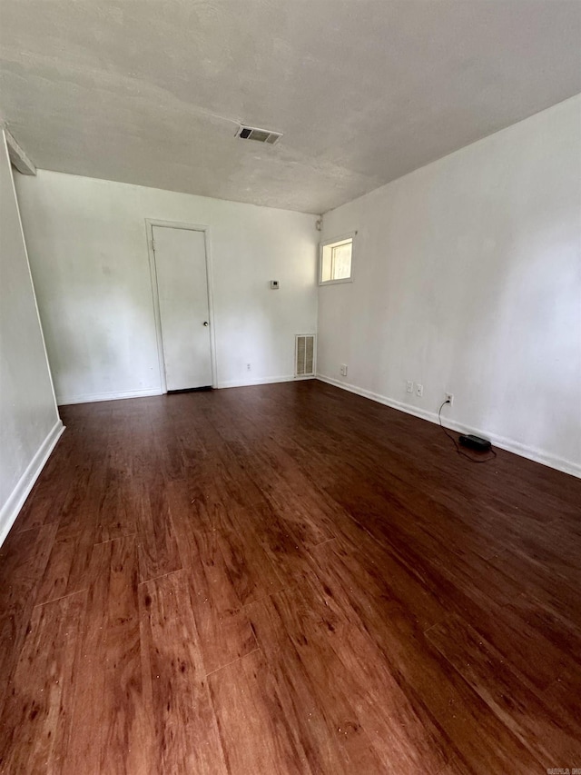 empty room with visible vents, wood finished floors, and baseboards