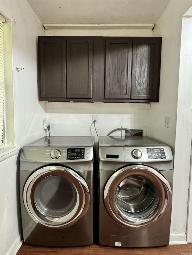 clothes washing area with wood finished floors, cabinet space, and washer and dryer