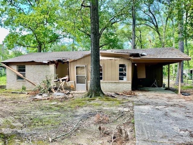 ranch-style home with board and batten siding, brick siding, driveway, and an attached carport