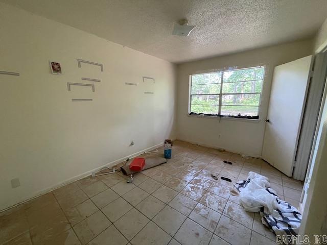 empty room featuring light tile patterned floors and a textured ceiling