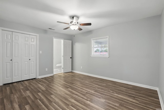 unfurnished bedroom with a closet, dark wood finished floors, ensuite bathroom, and baseboards