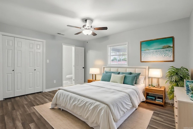 bedroom featuring a closet, ensuite bath, dark wood-style floors, a ceiling fan, and baseboards