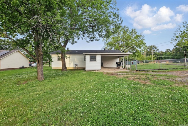 back of property featuring a yard, fence, and a carport