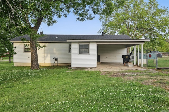 back of property featuring a yard, driveway, an attached carport, and fence