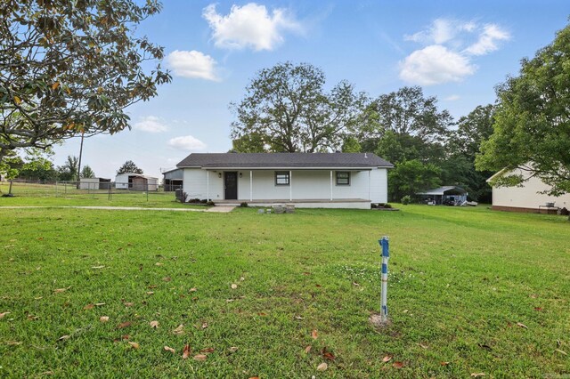 rear view of property with covered porch, fence, and a lawn