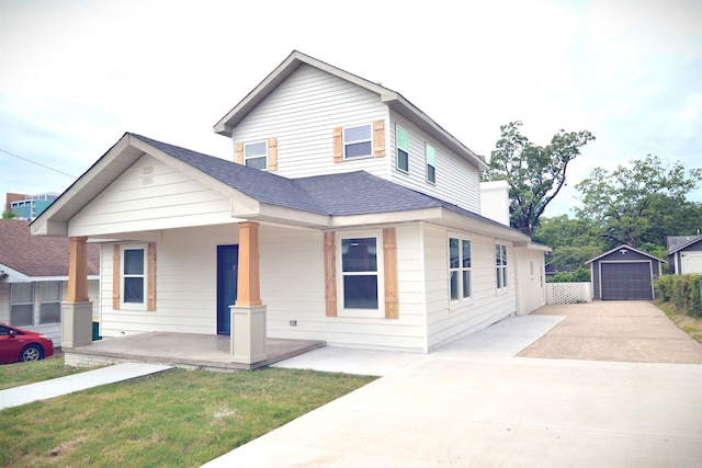 view of front facade featuring covered porch, concrete driveway, roof with shingles, an outdoor structure, and a detached garage