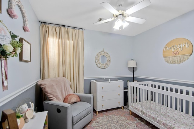 bedroom with ceiling fan and a crib