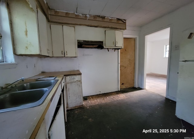 kitchen with concrete floors, white cabinetry, and a sink