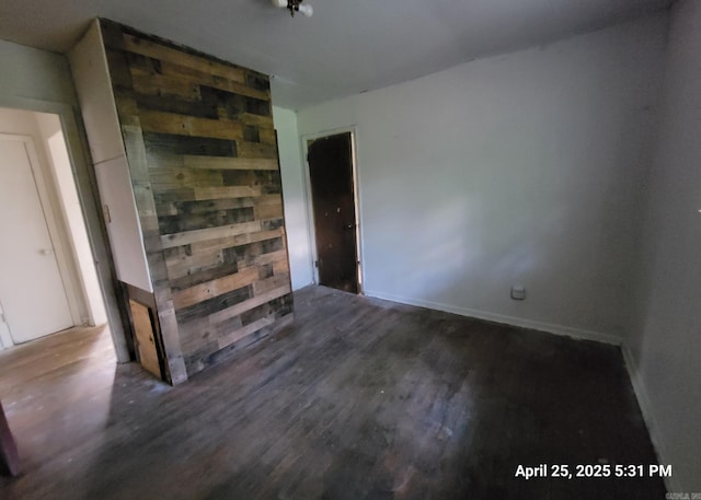 empty room with wooden walls, baseboards, and wood finished floors