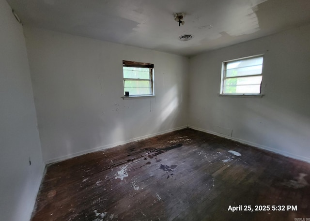 spare room with visible vents, baseboards, a healthy amount of sunlight, and hardwood / wood-style flooring