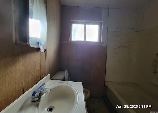 bathroom featuring a sink, toilet, and wood walls