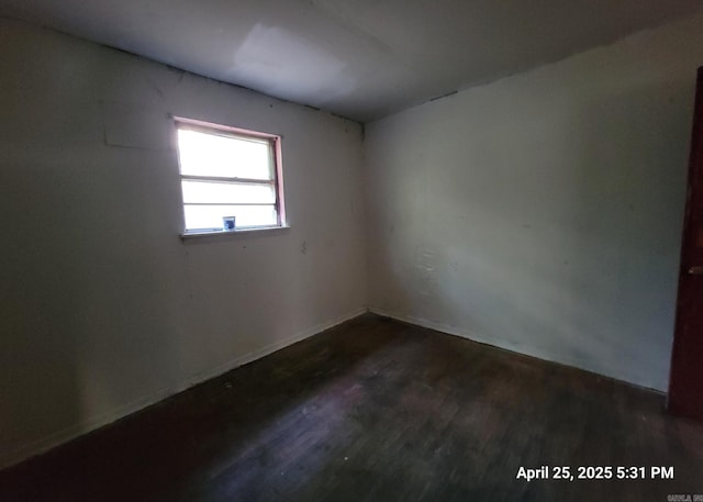 unfurnished room featuring dark wood-style flooring and baseboards