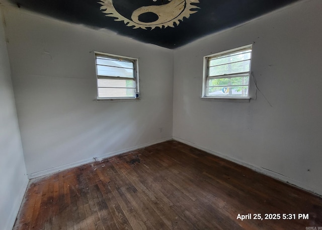 spare room featuring baseboards, plenty of natural light, and hardwood / wood-style flooring