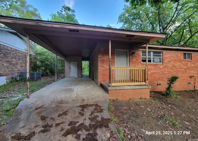 view of front facade featuring brick siding, central AC, crawl space, concrete driveway, and a carport