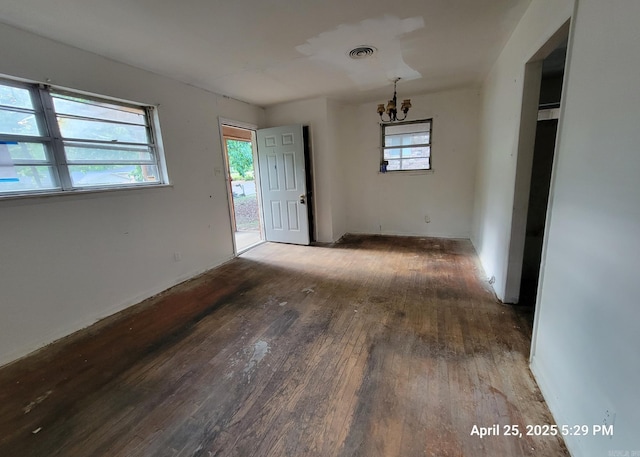unfurnished dining area with baseboards, a chandelier, wood finished floors, and visible vents