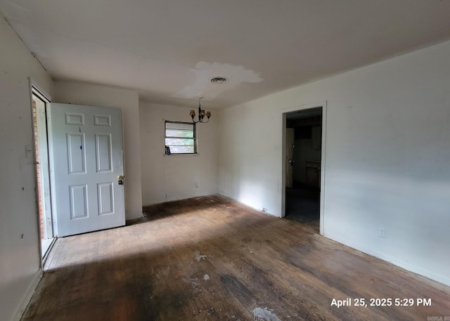 unfurnished dining area featuring a notable chandelier, baseboards, visible vents, and wood finished floors