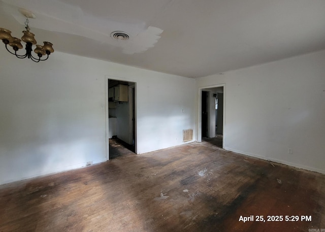 spare room featuring an inviting chandelier, visible vents, and wood finished floors