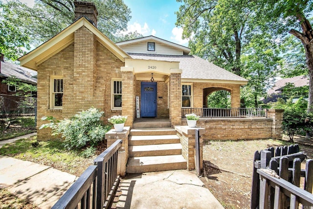 2420 Marshall St, Little Rock, AR 72206 - view of front of home featuring a chimney, brick siding, fence, covered porch, and roof with shingles