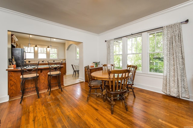 2420 Marshall St, Little Rock, AR 72206 - dining room featuring arched walkways, baseboards, wood-type flooring, and crown molding