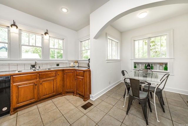 2420 Marshall St, Little Rock, AR 72206 - kitchen with a sink, black dishwasher, brown cabinetry, baseboards, and arched walkways
