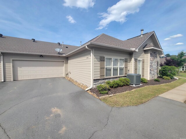 244 Mountain Terrace Cir, Maumelle, AR 72113 - view of home's exterior with stone siding, central AC, driveway, a shingled roof, and a garage