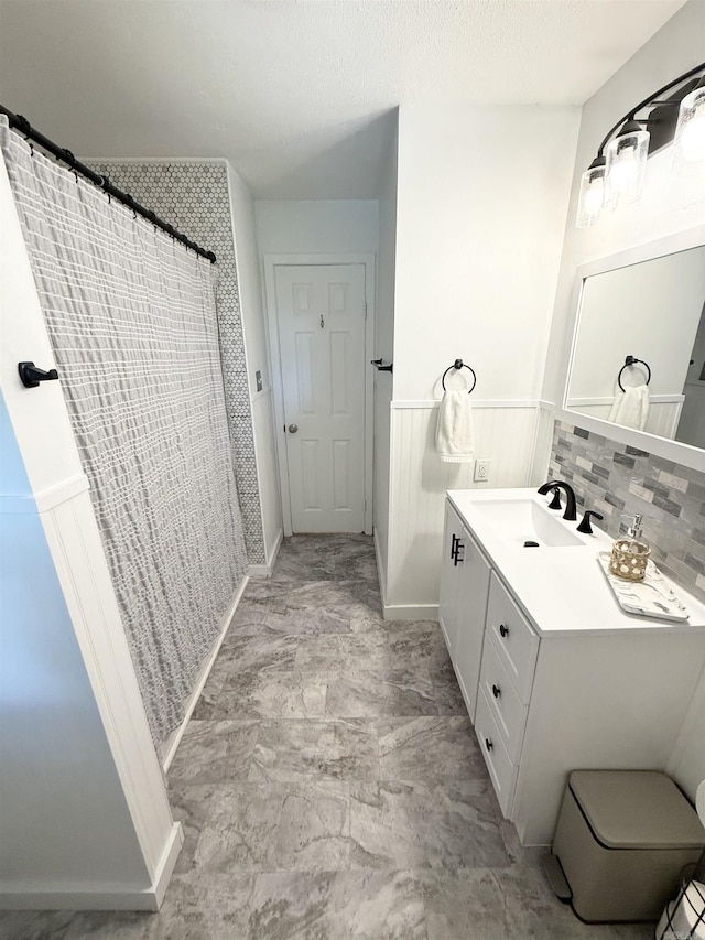 full bathroom featuring vanity, a shower with curtain, and a wainscoted wall