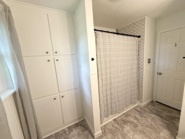 bathroom featuring a wainscoted wall and curtained shower