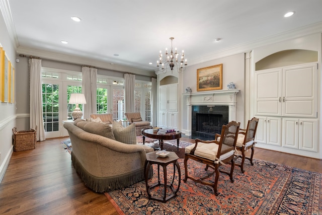 living area with dark wood finished floors, a chandelier, ornamental molding, and a high end fireplace