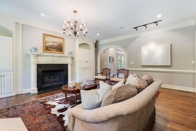 living area with wood finished floors, track lighting, arched walkways, ornamental molding, and a high end fireplace
