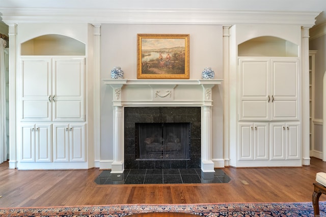 room details featuring baseboards, a tiled fireplace, crown molding, and wood finished floors