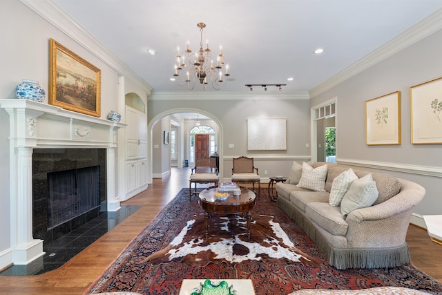 living area featuring ornamental molding, a wealth of natural light, a chandelier, and arched walkways