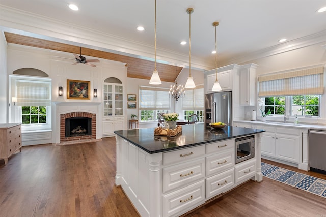 kitchen featuring a ceiling fan, a brick fireplace, white cabinets, dark wood finished floors, and appliances with stainless steel finishes